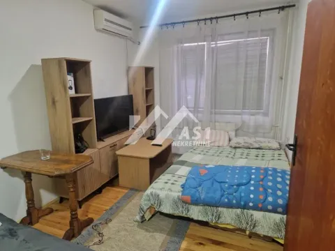 Nameštena spavaća soba sa krevetom, televizorom i drvenim nameštajem. - image 3