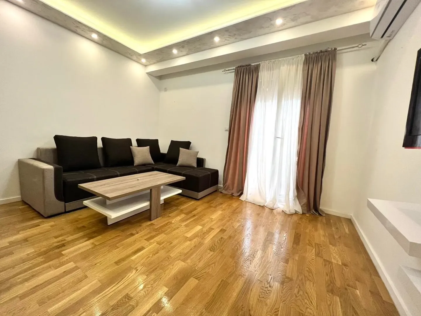 Dnevna soba sa garniturom, klub stočićem i drvenim podom.