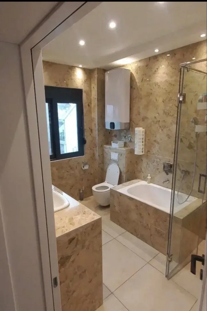 Modern tiled bathroom with a bathtub and a shower cabin.