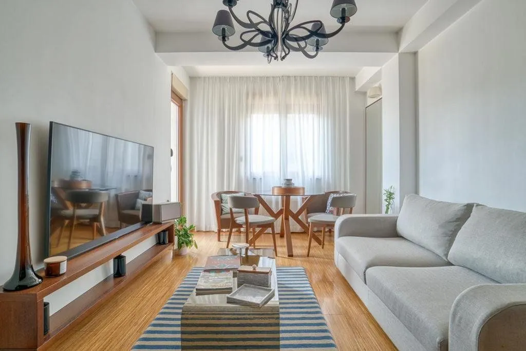 Living room with a sofa, TV, and a dining table in the background.