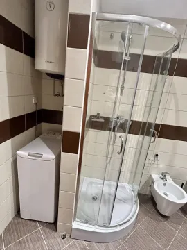 A bathroom featuring a shower cabin, bidet, and washing machine. - image 10
