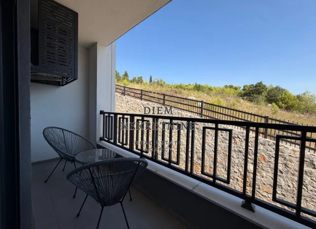 Covered balcony with seating furniture and a view of the surrounding greenery.