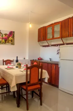 Trpezarija sa stolom za ručavanje i ugrađena kuhinja sa frižiderom. - image 2