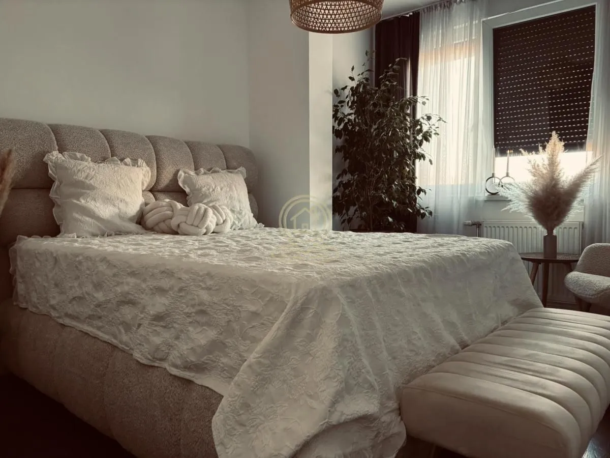 Udobna spavaća soba sa velikim bračnim krevetom i prozorom sa roletnama.