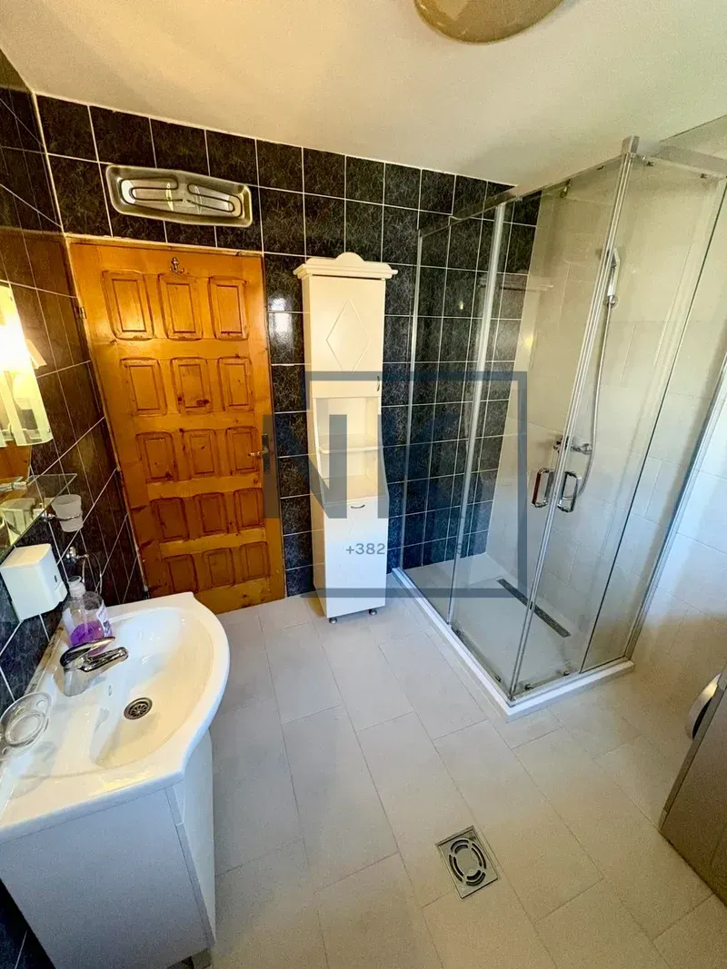 Bathroom with a shower cabin, washbasin, and wooden door.