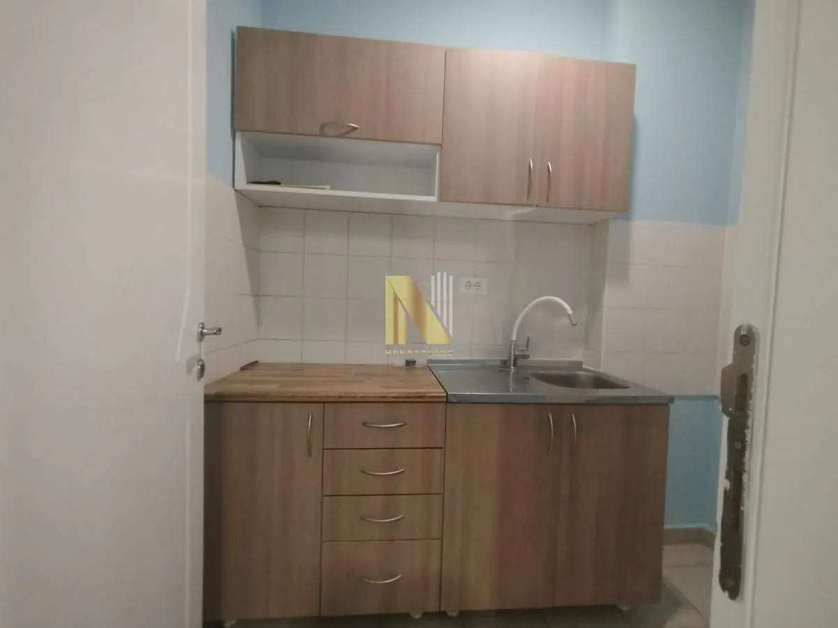 Manja kuhinja sa drvenim elementima i sudoperom.
