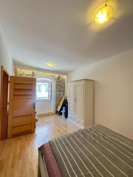 Namještena spavaća soba sa drvenim podom, ormarom i kamenim detaljima na zidu. - image 10