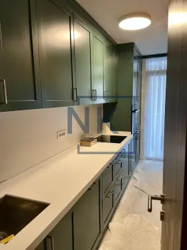 Long kitchen with dark green cabinets and a white countertop. - image 4
