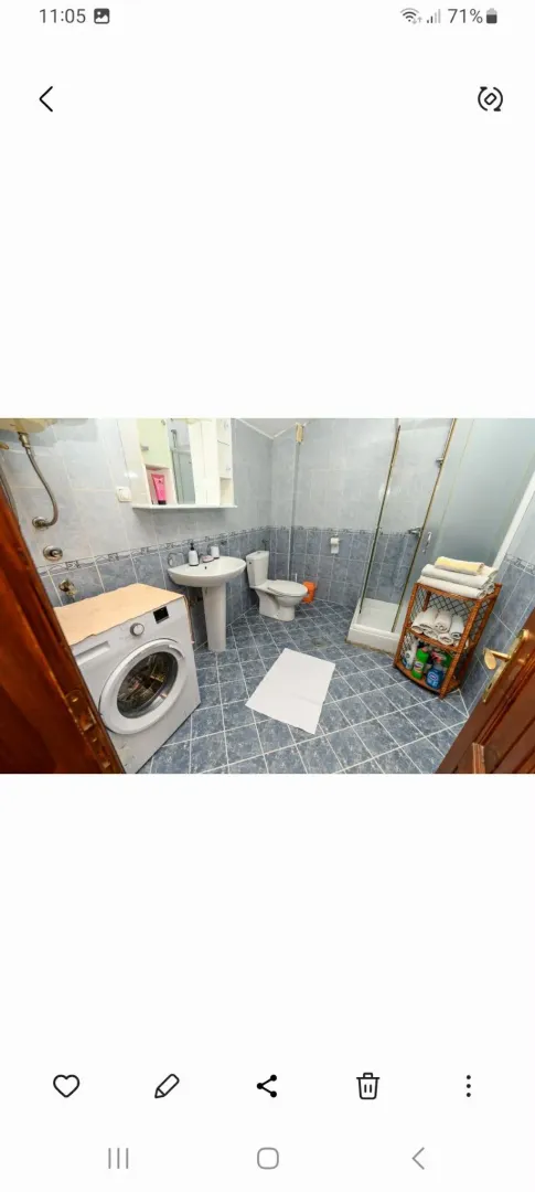 Bathroom with tiles, shower cabin, sink, and washing machine.
