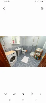 Bathroom with tiles, shower cabin, sink, and washing machine. - image 15
