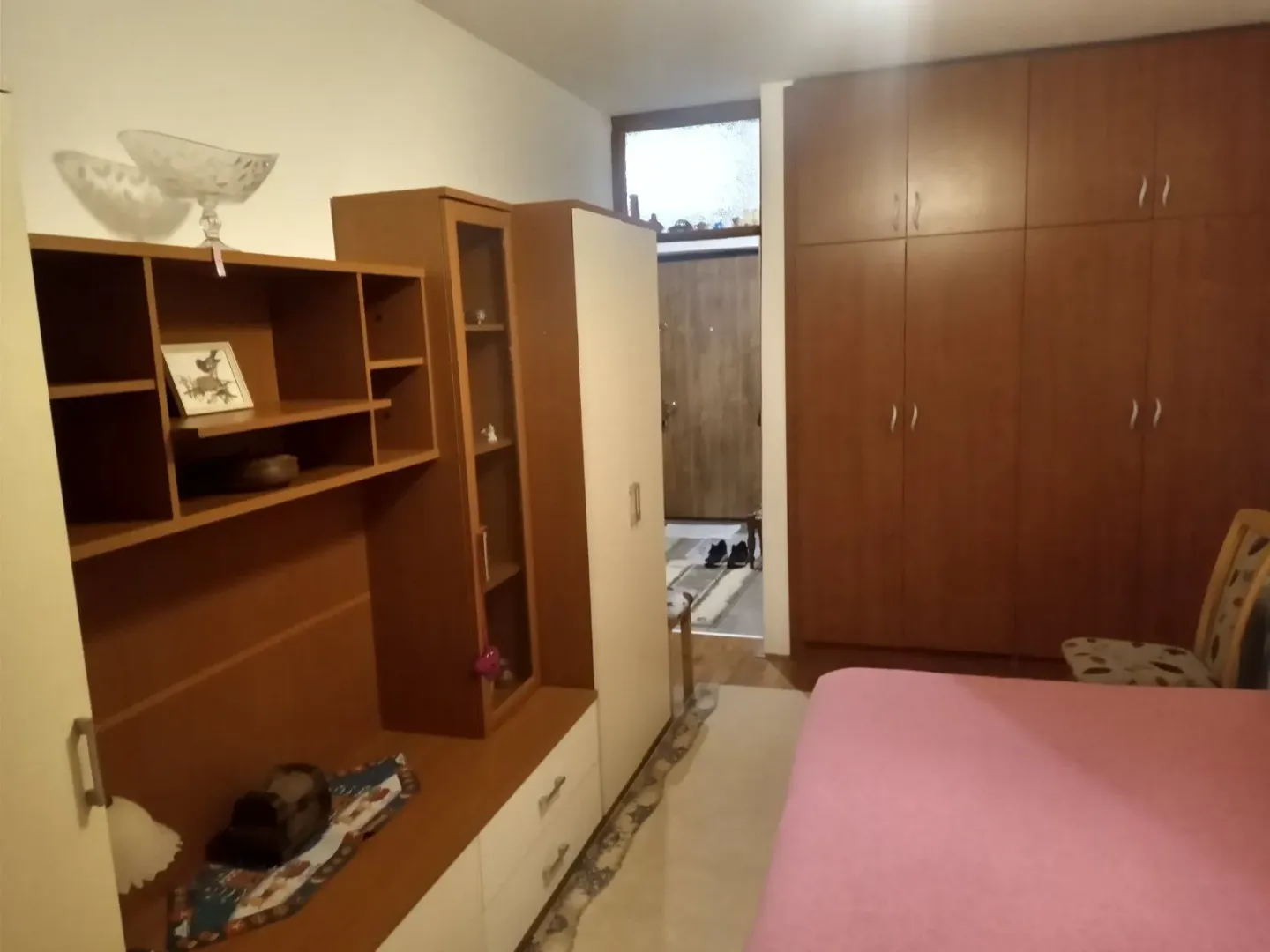 Spavaća soba sa drvenim ormarom, komodom i krevetom.