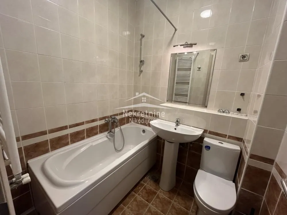 Bathroom equipped with a bathtub, washbasin, and toilet featuring ceramic tiles on the walls and floor.