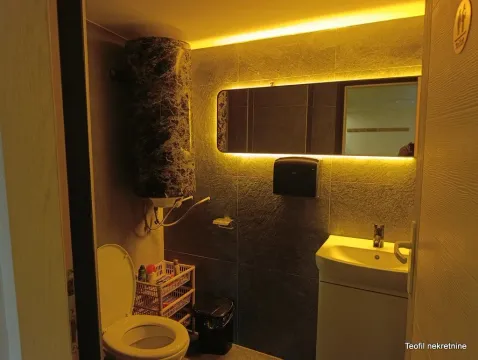 Small bathroom with a sink, toilet, and backlit mirror. - image 9