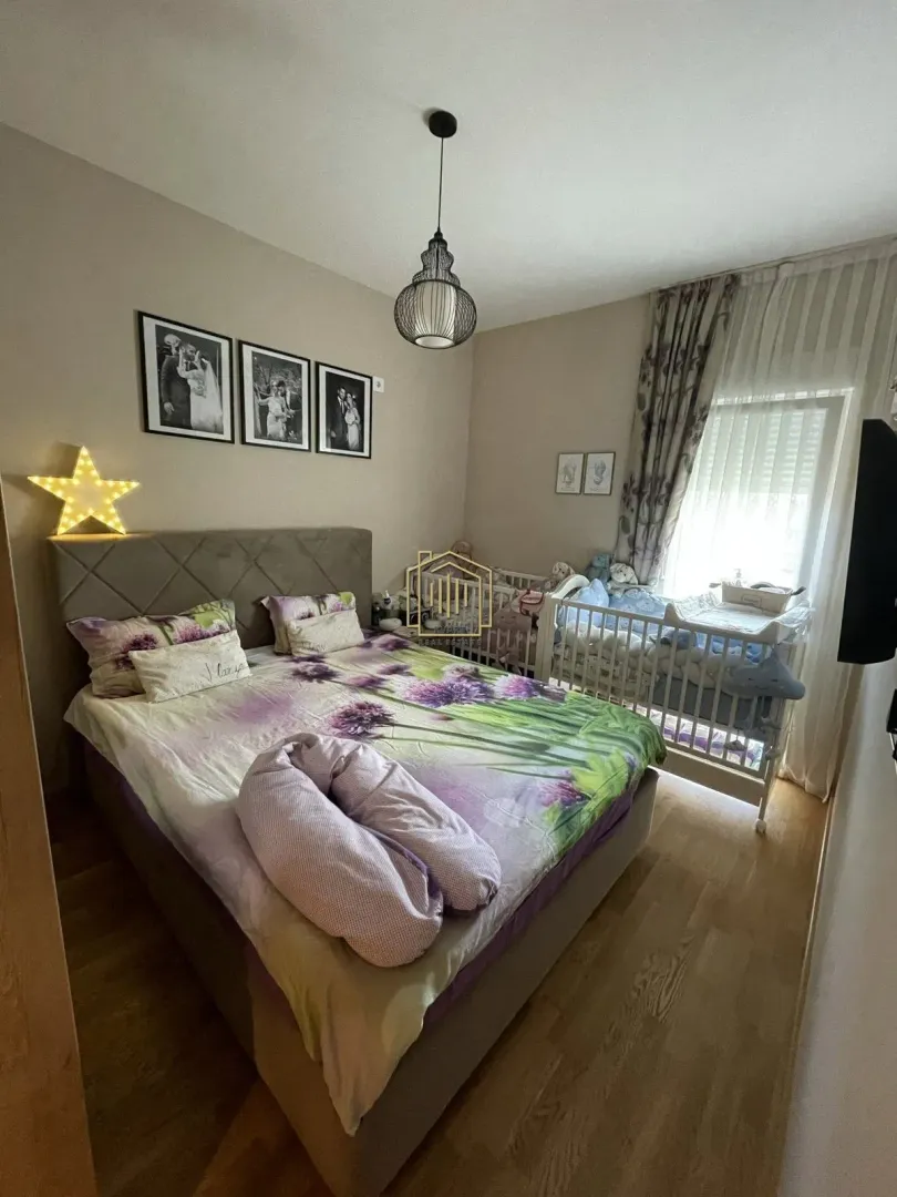 Prostrana spavaća soba sa bračnim krevetom i krevetcem za bebe.