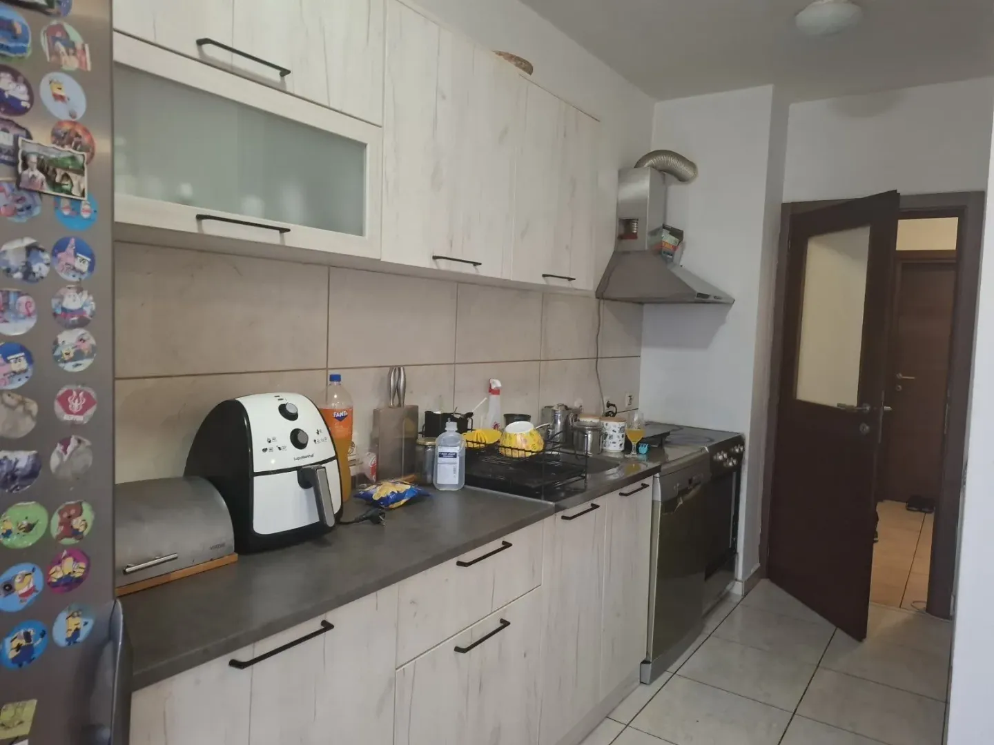 Svijetla kuhinja sa bijelim elementima i aparatima na radnoj površini.