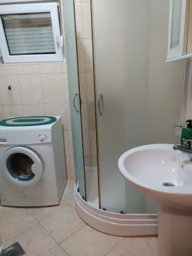 A bright bathroom featuring a shower cabin and a washing machine. - image 3