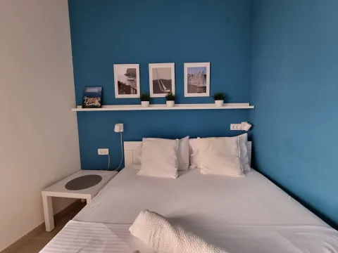 Spavaća soba sa bračnim krevetom i plavim zidom. - image 14