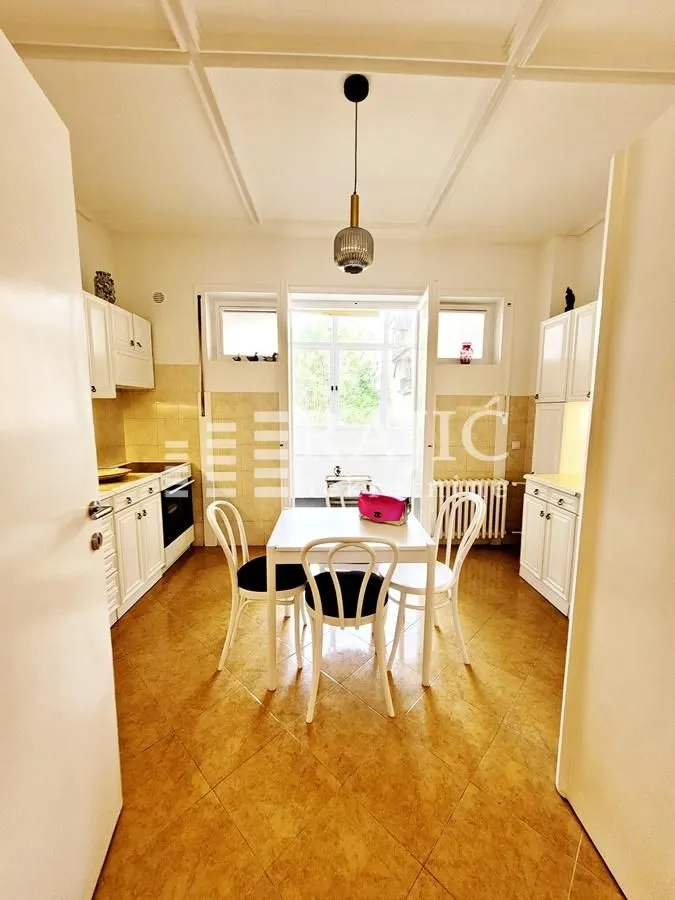 Bright kitchen with white cabinetry and a dining table in the center.