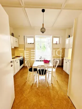Bright kitchen with white cabinetry and a dining table in the center. - image 4