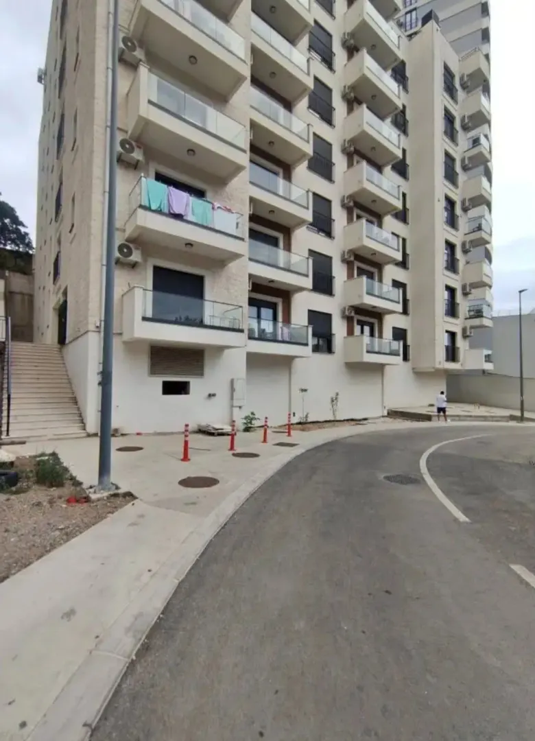 Exterior view of a residential building with balconies and driveway.