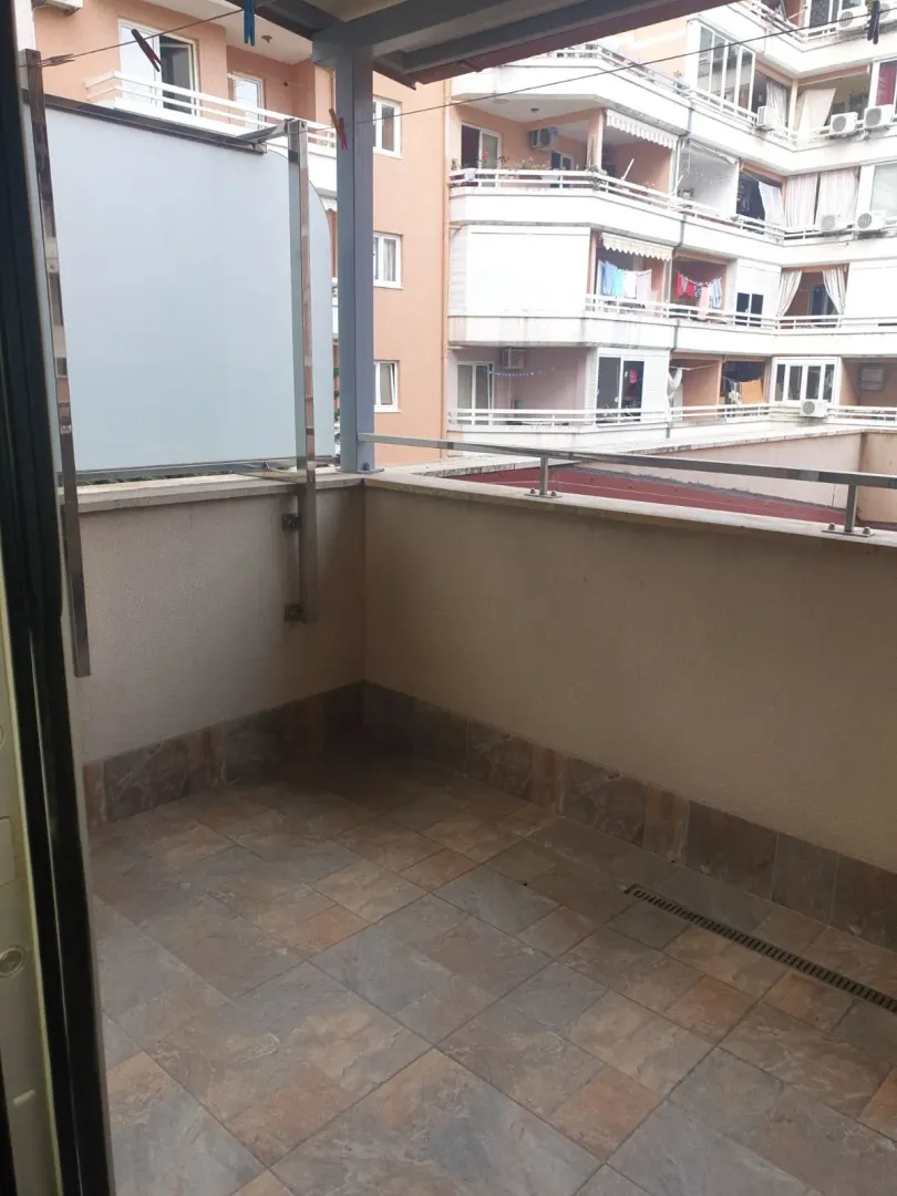 Prostrana terasa sa pločicama i pogledom na susjedne zgrade.