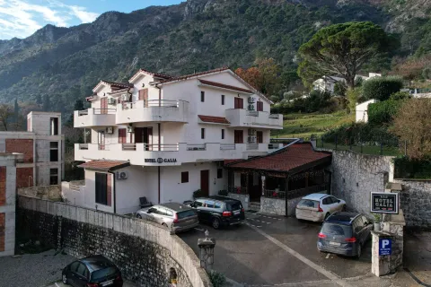Pogled na spoljašnjost zgrade sa parkingom i planinskim pejzažem u pozadini. - image 2