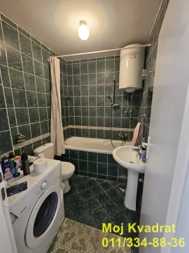 Kupatilo obloženo zelenim pločicama sa kadom, umivaonikom, WC šoljom i mašinom za veš. - image 6