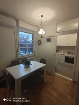 Trpezarija sa stolom i stolicama i pogledom na kuhinju kroz klizna vrata. - image 10