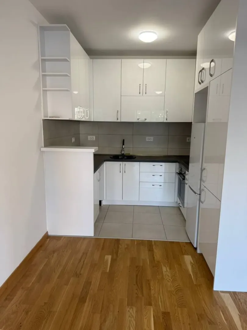 Small white kitchen with a sink, cabinetry, and refrigerator.