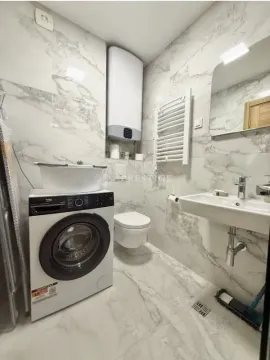 Modern bathroom lined with marble tiles featuring a washing machine. - image 10
