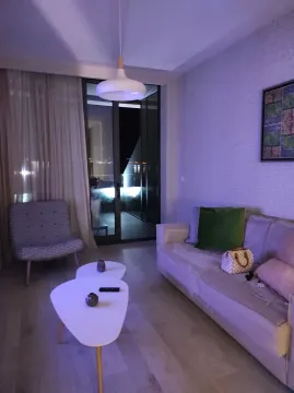 Living room with a sofa, armchair, and balcony access. - image 8