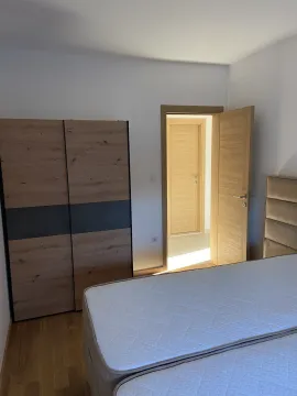 Svijetla spavaća soba sa modernim ormarom, krevetom i otvorenim vratima. - image 6