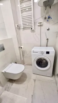 Moderne kupatilo sa bijelim pločicama, konzolnom šoljom i veš mašinom. - image 7