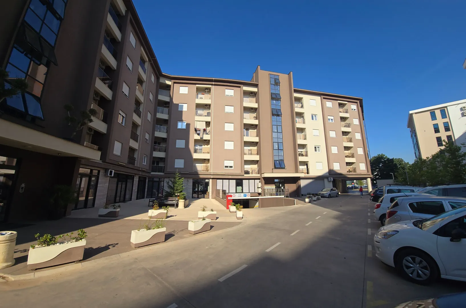 Exterior of a modern residential building with a courtyard and parking.