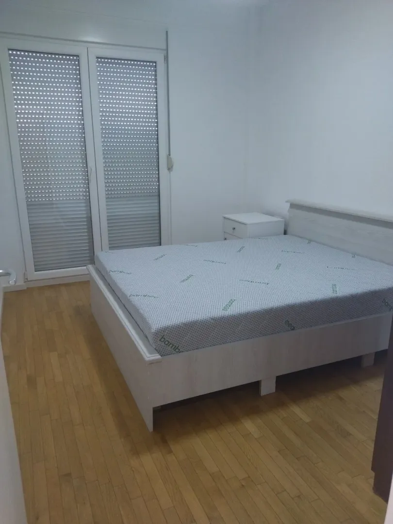 Svjetla spavaća soba sa bračnim krevetom i parketom.