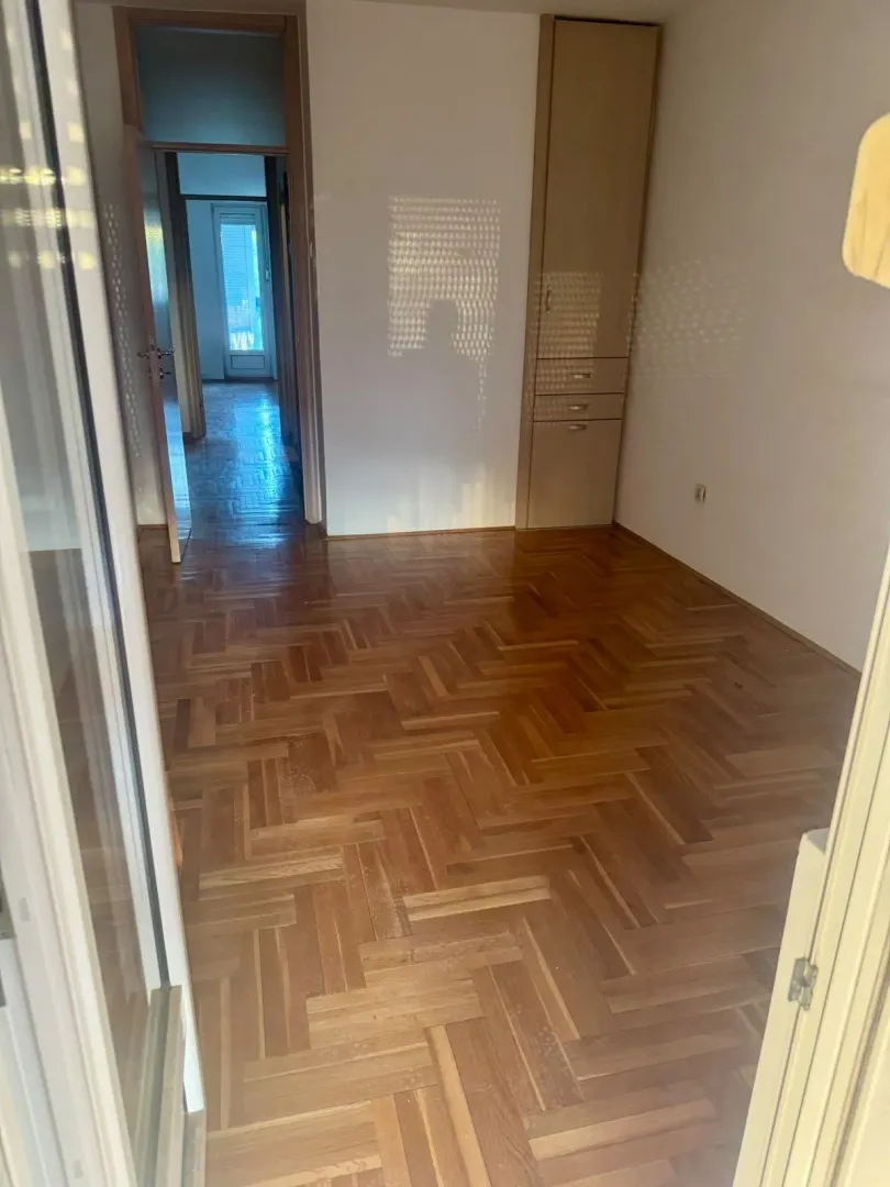 Empty room with parquet flooring and built-in closet, looking towards the hallway.