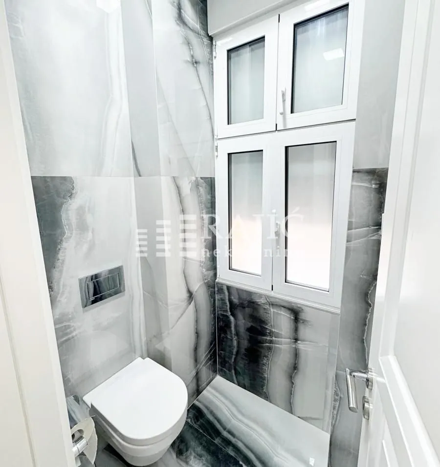 Modernly equipped bathroom with ceramic tiles and built-in fixtures.