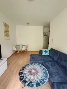 Living room with a sofa, coffee table, and a dining area in the background. - image 3