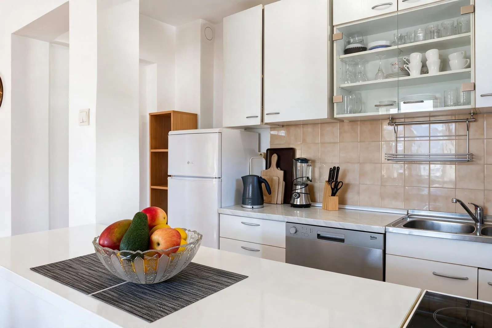 Bright and tidy kitchen with white cabinetry and a sink.