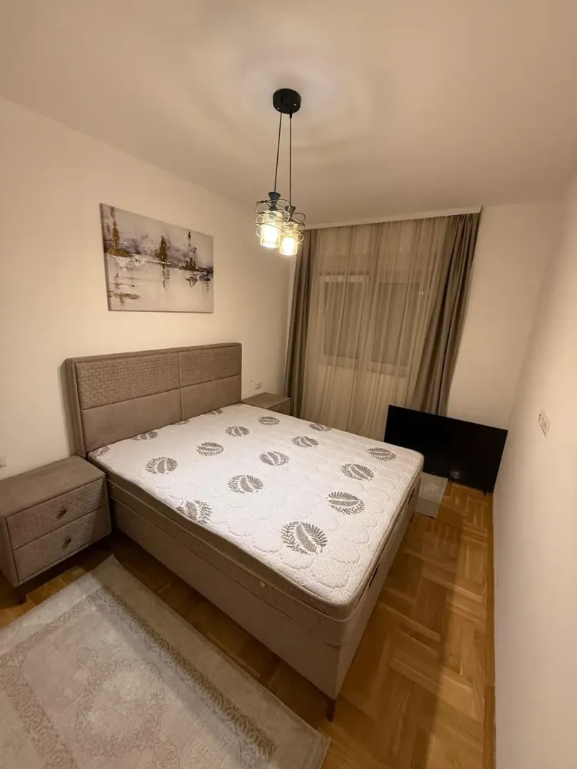 A furnished bedroom with a double bed, nightstands, and lighting.