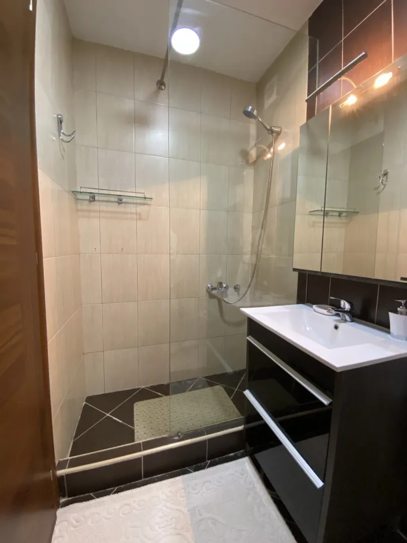 A bathroom with a glass shower cabin and a modern sink.