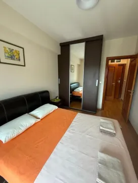 Spavaća soba sa bračnim krevetom, garderoberom sa ogledalom i ulaznim vratima. - image 6