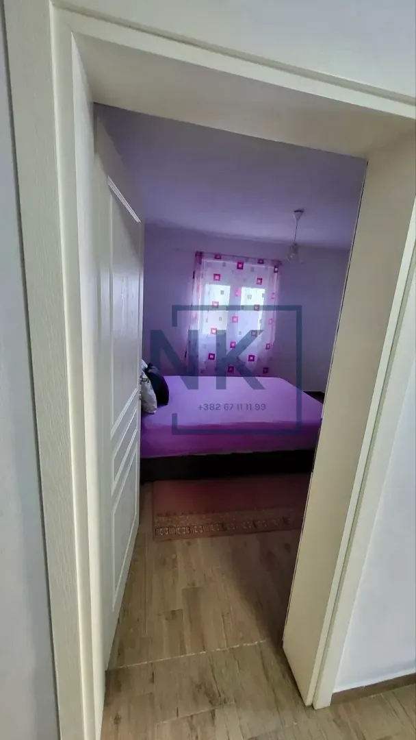 View from the hallway into a bedroom with a bed and a window.