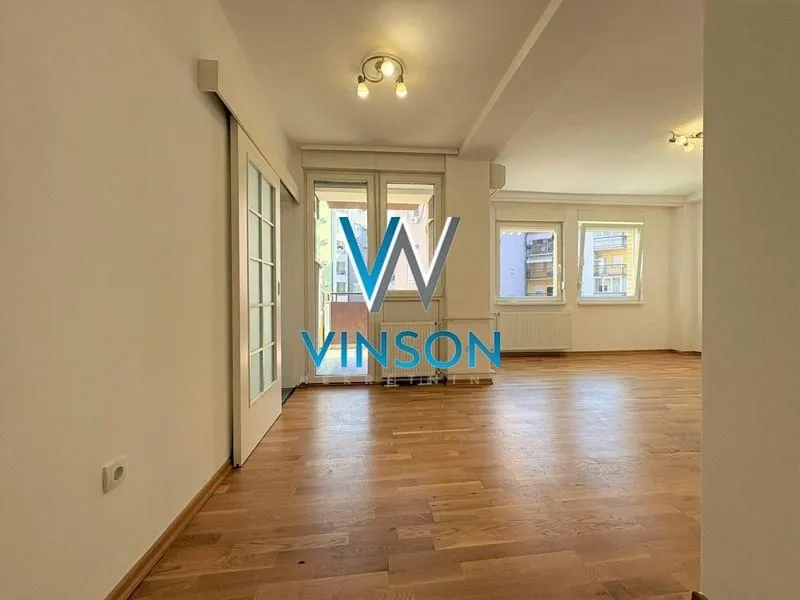 Spacious living room with wooden parquet flooring and access to the terrace.