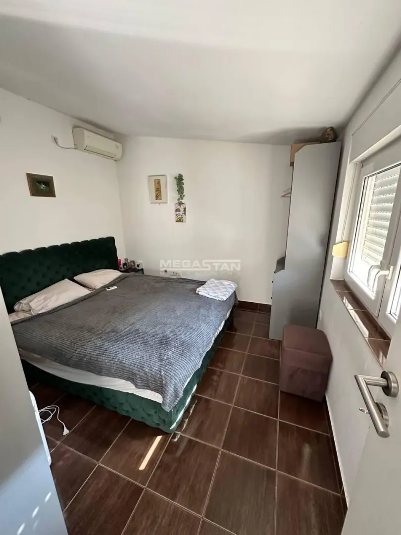 Spavaća soba sa bračnim krevetom, ormarom i prozorom.