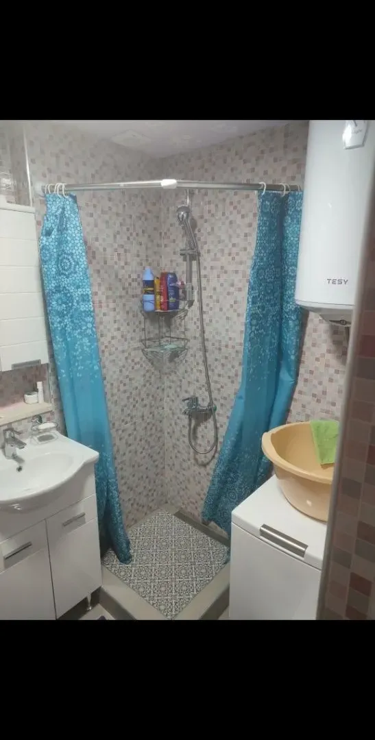 Small bathroom with a shower cabin, washbasin, and water heater.