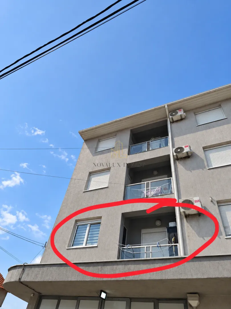 Pogled na spoljašnjost stambene zgrade sa balkonom označenim crvenim krugom.