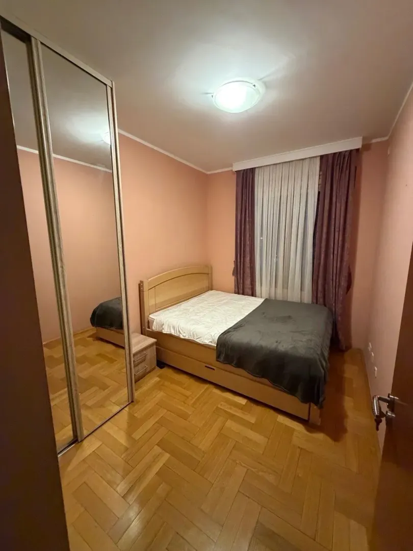 Bedroom with a double bed, mirrored wardrobe, and parquet flooring.
