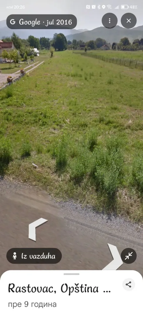 Pogled na zelenu parcelu i okolinu sa putem u blizini.