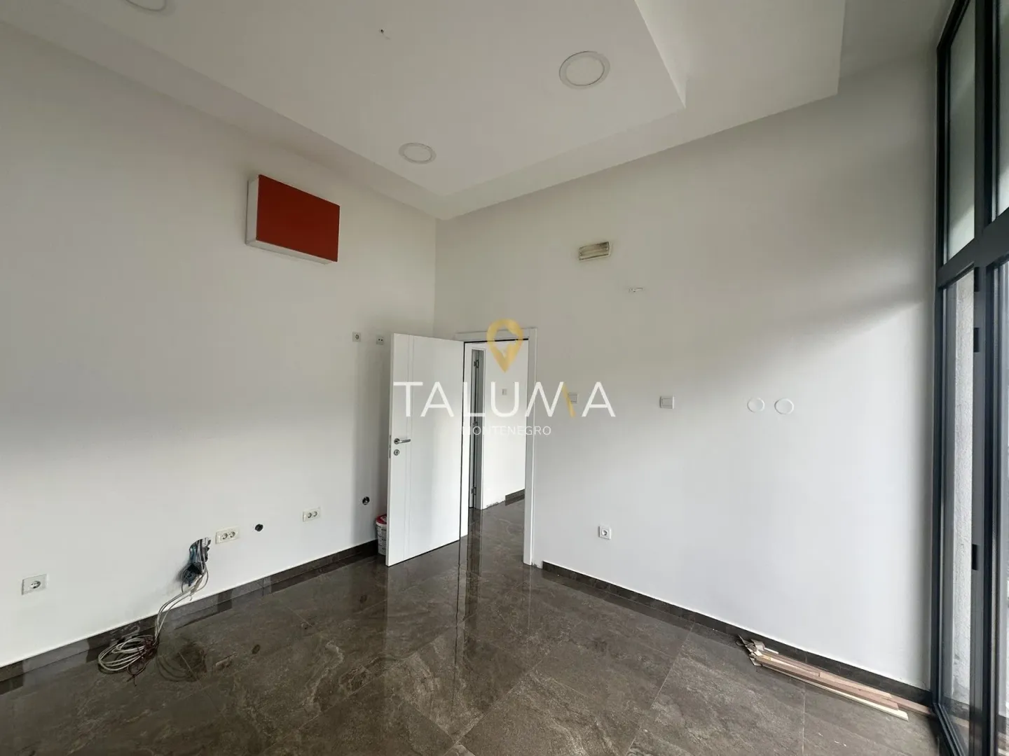 Empty bright room with tiled flooring and an open door.